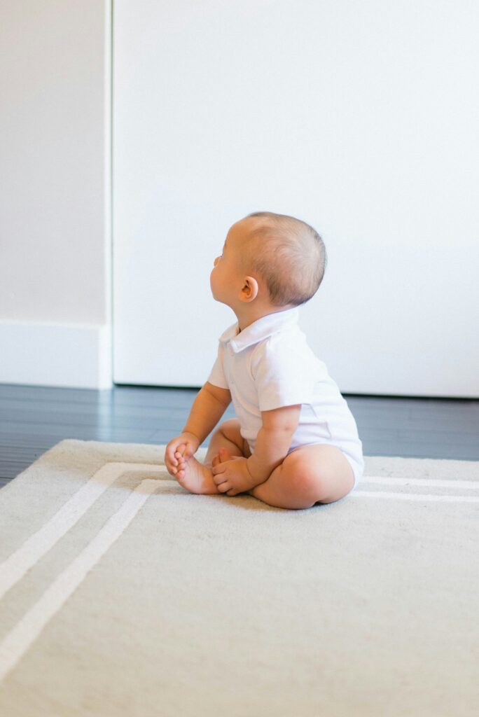 Baby sitzt allein auf einem hellen Teppich