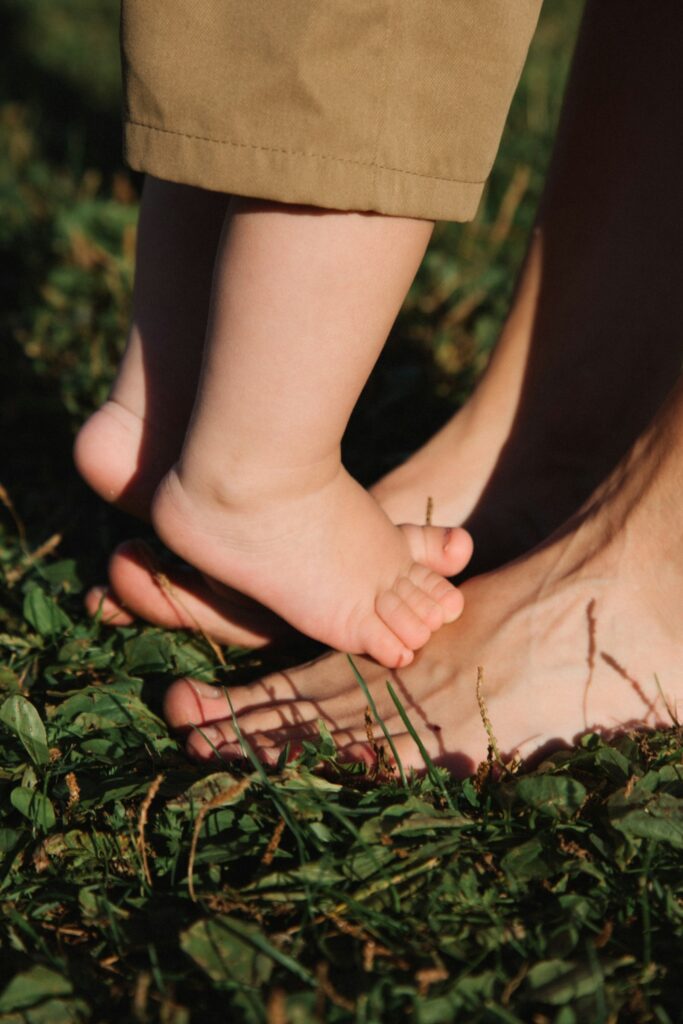 Babyfüße auf den Füßen eines Erwachsenen – Kindergeld für die Familie