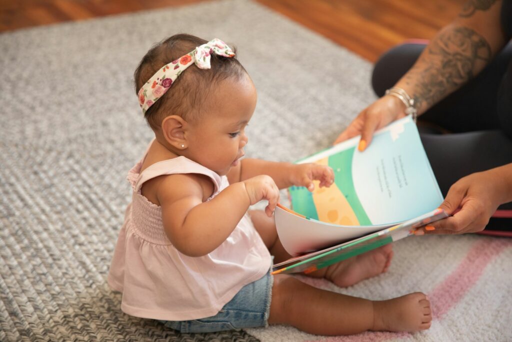 Wachfenster Baby: waches Baby schaut neugierig in ein Bilderbuch